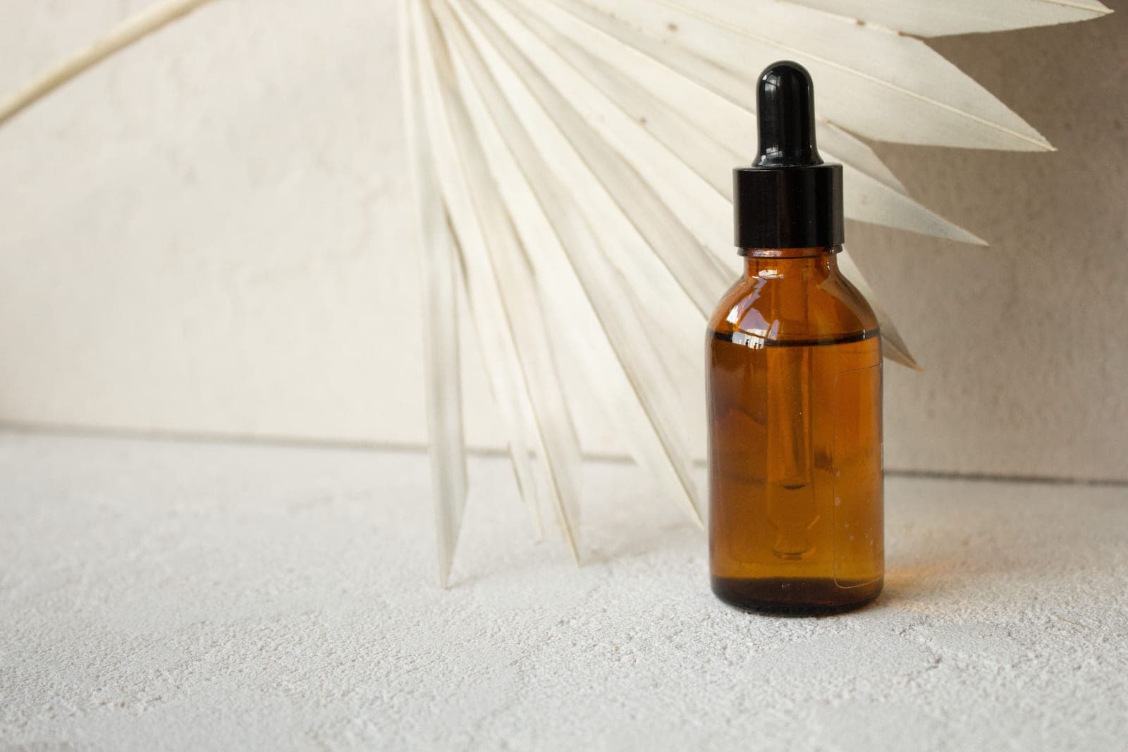 A glass dropper bottle of squalane facial oil on a warm, minimal background